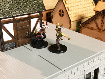 Jacqueline and Christopher fight with swords on a building roof (DnD minis)
